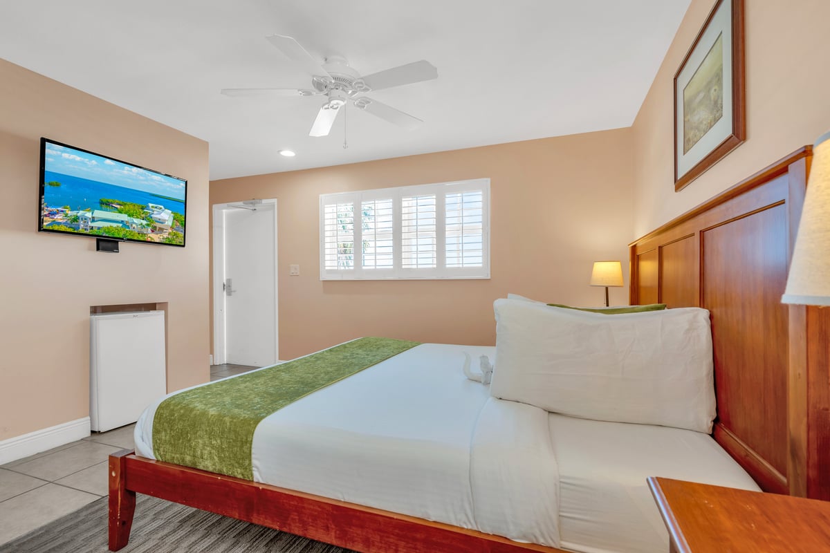 NK5 Deluxe Oceanfront King, bed facing open balcony doors with sand and turquoise water beyond