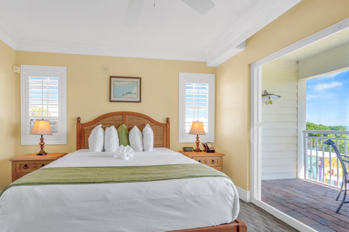 King guest room with a private balcony at Dove Creek, doors open to the outdoor seating
