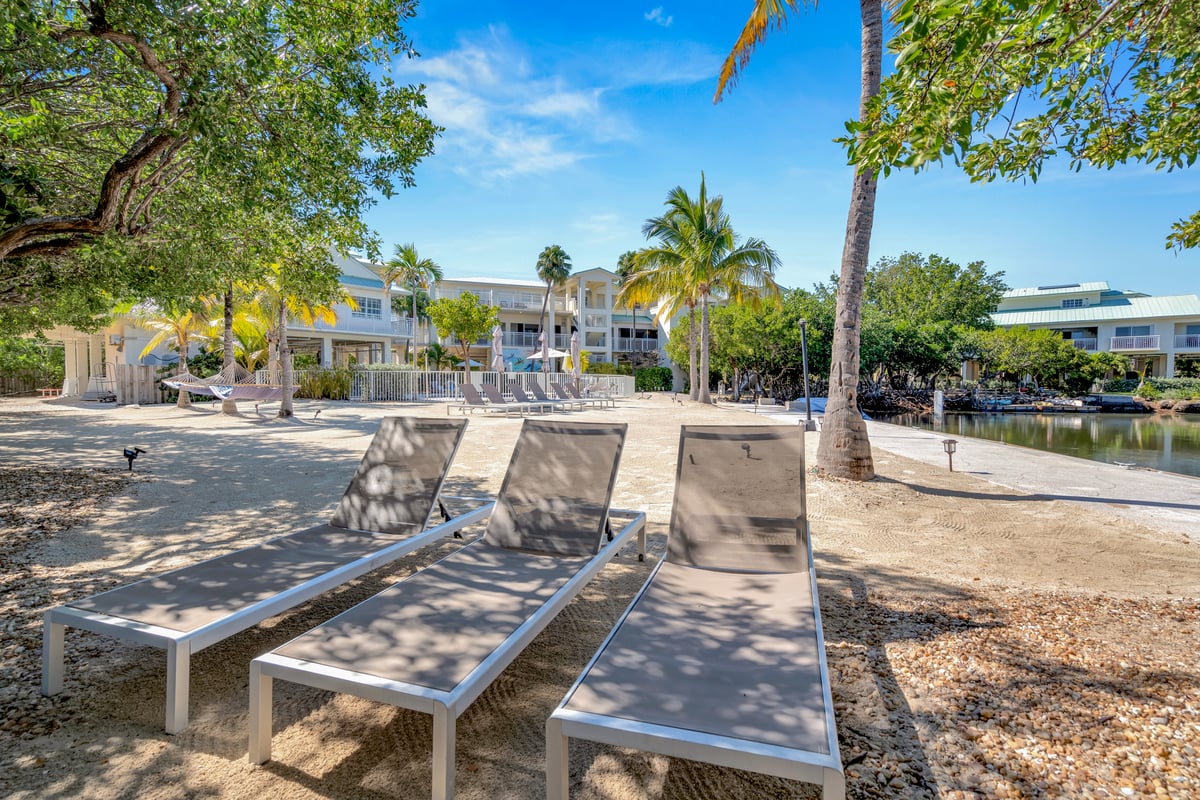 Loungers and an open umbrella set out on the sand directly in front of Dove Creek Resort & Marina