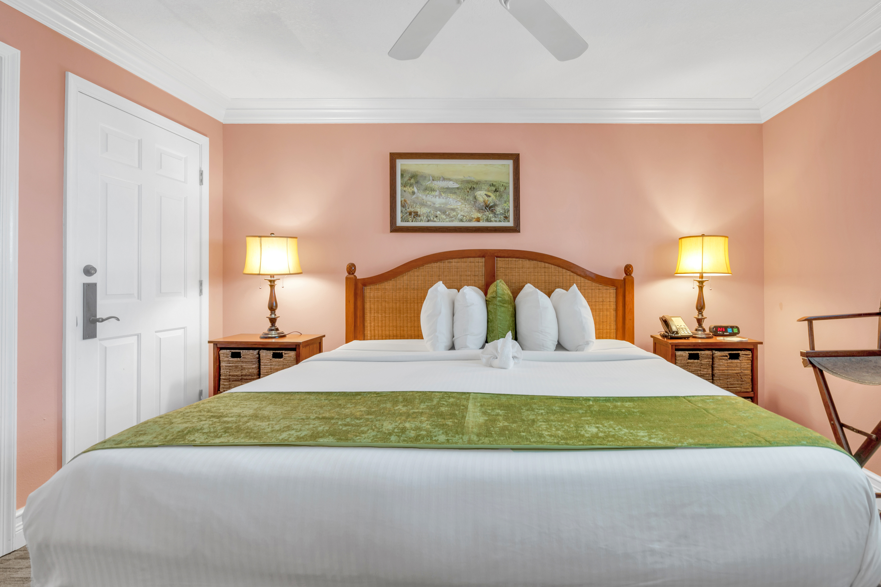 NQQ4 Deluxe Double Queen with Balcony — two queen beds with slate runners facing open balcony doors, white balcony chairs outside and palms along the street beyond