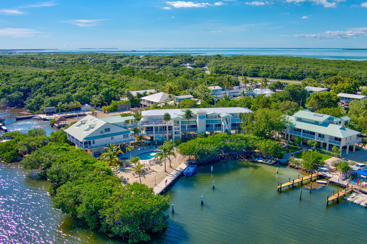 Wide aerial over Dove Creek Resort & Marina in Key Largo, the buildings, pool and marina set against the creek and open water